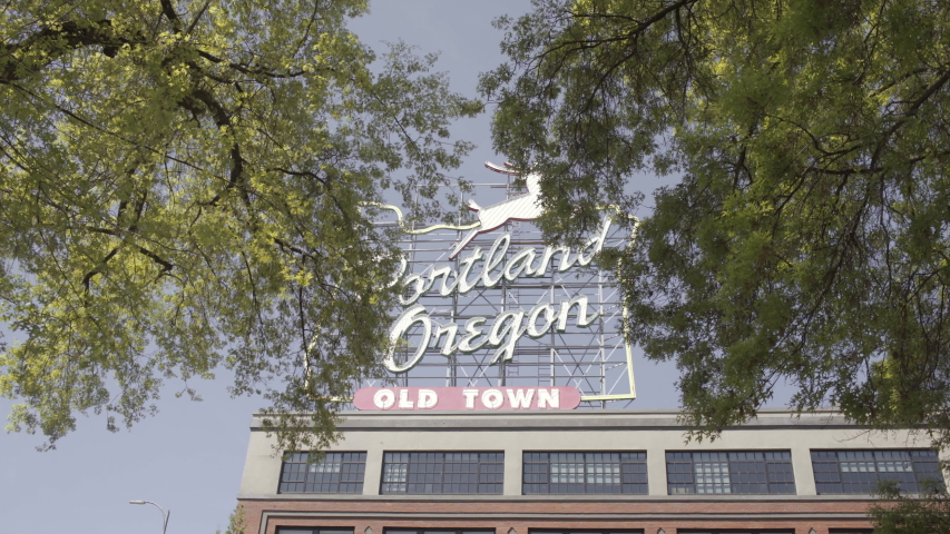 Wide moving low angle shot of Portland Oregon neon sign on a sunny day, USA