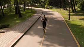 Man running in Park sunny day Follow shot video. Sportsman Runner Athlete training 
