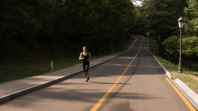 Man running in Park sunny day Follow shot video. Sportsman Runner Athlete training 