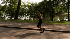 Man running in Park sunny day Follow shot Side view video. Sportsman Runner Athlete training 