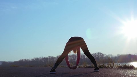 athletic woman doing exercises during sunrise or sunset. sportive girl on the river bank