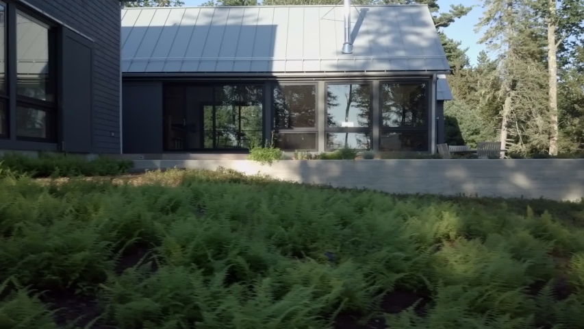 Side view of a custom designed vacation getaway home on the coast of New England in the state of Maine. Dolly shot.
