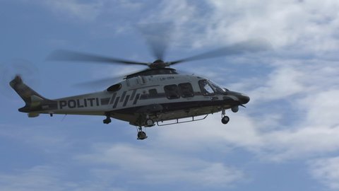 oslo airport norway - ca july 2019: brand new norwegian police helicopter leonardo helicopters aw169 fly by panning right slow motion sunny day white clouds