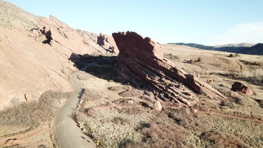 AERIAL: pushing towards from a road twisting around a giant boulder in the Red Rocks Park in Colorado.