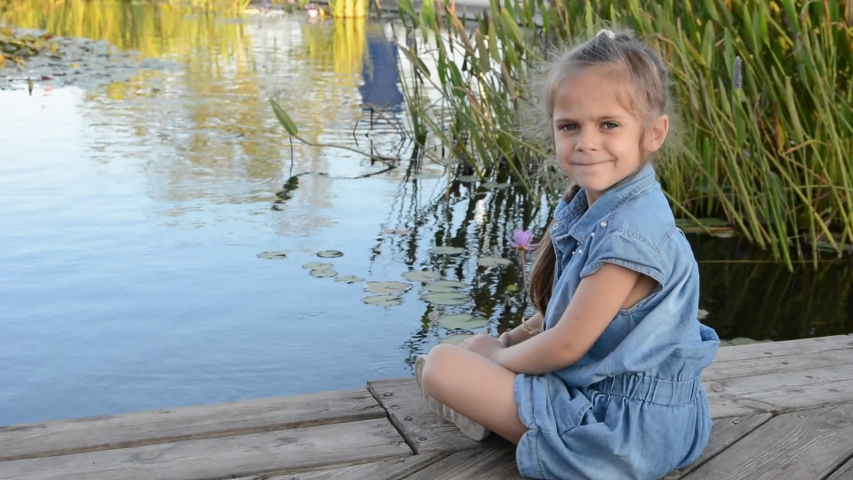 Toddler girl watching colorful Koi or carps fish in the pond, petting zoo