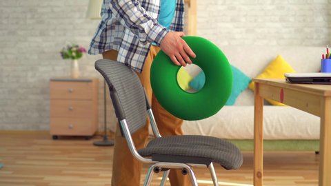 man sits on a round orthopedic pillow and starts working on a laptop close up