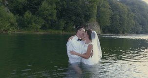 Beautiful wedding couple standing in the river at the sunset. Drone 4K footage. Carpathian Mountains in Ukraine.