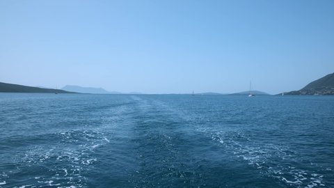 Greece Sailing yacht sails on open sea on waves of blue sea, white trail with foam after ship waterway. Trail on surface water behind moving motorboat. Horizon shores of island. Travel. Tourism