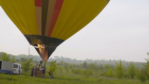 Detail of flying colorful cloud hopper hot air balloon inflated with fire flame 4K
