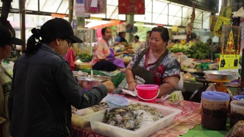 Banmai, Phitsanulok / Thailand - 12 29 2018: Lady buying from a market vendor and her friend comes in and dances in Banmai Fresh Market Phitsanulok Thailand