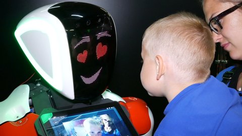 Chelyabinsk, Chelyabinsk region / Russia: 07.10.2019: Robot's face and child's face. Baby communicates with robot, the robot responds to the greeting and supports the conversation with emotions.