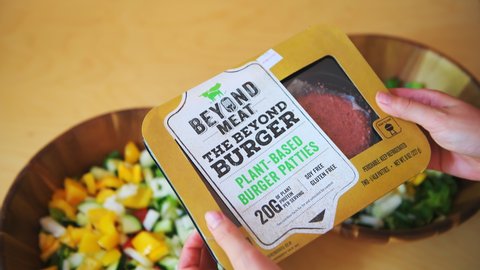 Aspen, USA - June 29, 2019: Beyond meat plant-based protein burger package with woman holding brand by salad bowls