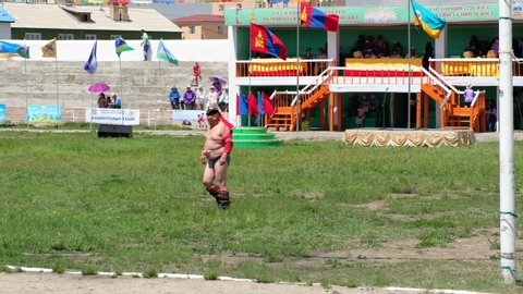 ALTAI CITY, MONGOLIA - JULY 06, 2017:  Overweight mongolian wrestler crossing sport stadium of Altai city in south-west of Mongolia. 