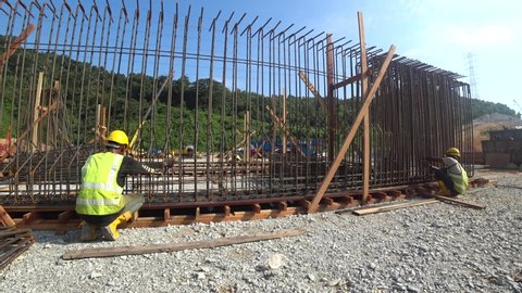 KUALA LUMPUR, MALAYSIA -MARCH 29, 2018: Construction workers fabricating steel reinforcement bar to form reinforcement concrete at the construction site. They tied it together using the tiny wires
