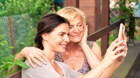 Happy daughter taking selfie photo with her mum on the porch in garden, 4K
