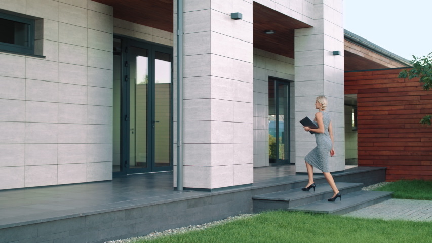 Business woman entering office building. Elegant woman going up stairs in modern building with laptop. Female boss arriving work. Business woman walking up stairs at luxury house.