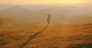 Children playing outside. Happy traveler boy playing with airplane toy on sunny day in park. 4K slow motion video. Child runs on top of mountain at sunset. Journey to the Edge of the Universe
