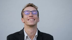 Front view of smiling young Caucasian male face in spectacles standing outside, looking at camera, laughing, moving, talking. Lifestyle concept