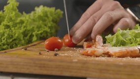 Chef cuts cherry tomato in half with sharp knife. Slow motion video