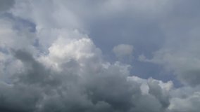 Dramatic rain clouds on dark sky background before thunder storm.  Puffy fluffy white & grey clouds in dramatic fast moving motion on beautiful horizon blue sky with sunlight & sun rays, TimeLapse
