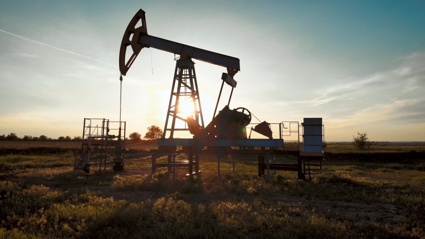 Silhouette of working oil pump from oil field at sunset. The industrial equipment. Royalty-Free Stock Footage #1033222385