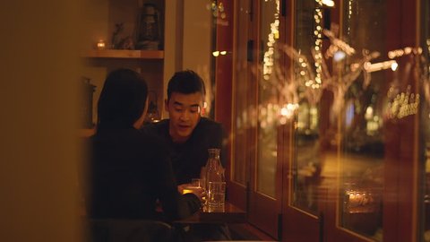 A young couple talking on a romantic dinner date, through the window 庫存影片