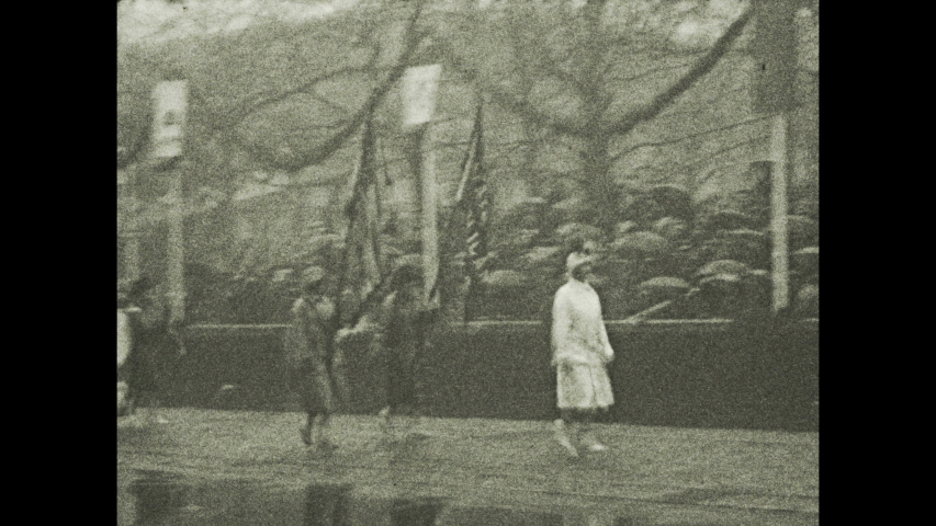 1920s: Parade. Spectators. Women carry banners. Marching band.