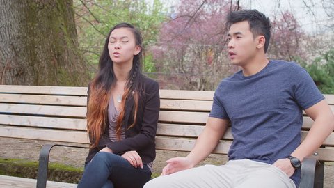 A young couple talking on a park bench