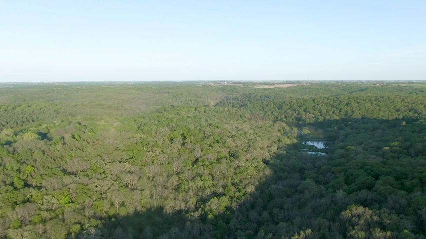 Aerial forward moving shot over a thick forest in the mountains of Wisconsin during dusk. It
