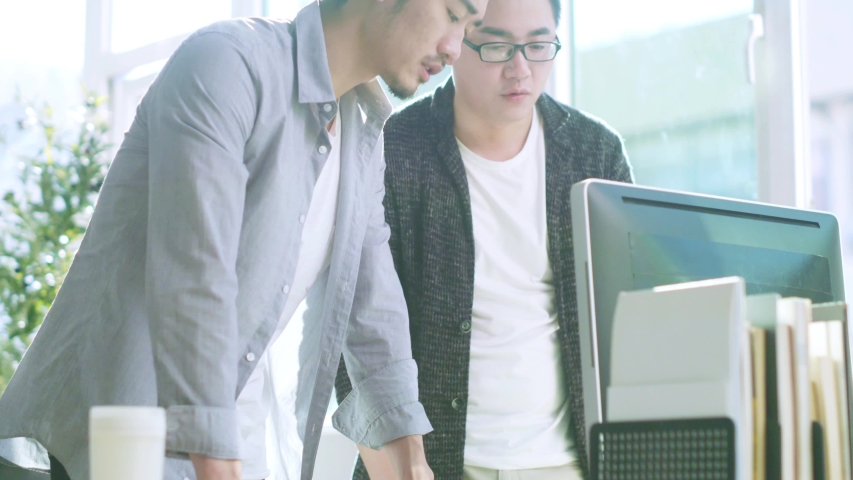 two young asian businessmen discussing business in office using desktop computer Royalty-Free Stock Footage #1033245518