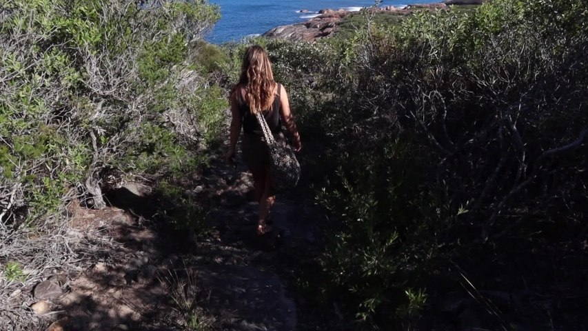 Woman walking on hiking trail with view of beautiful coastline