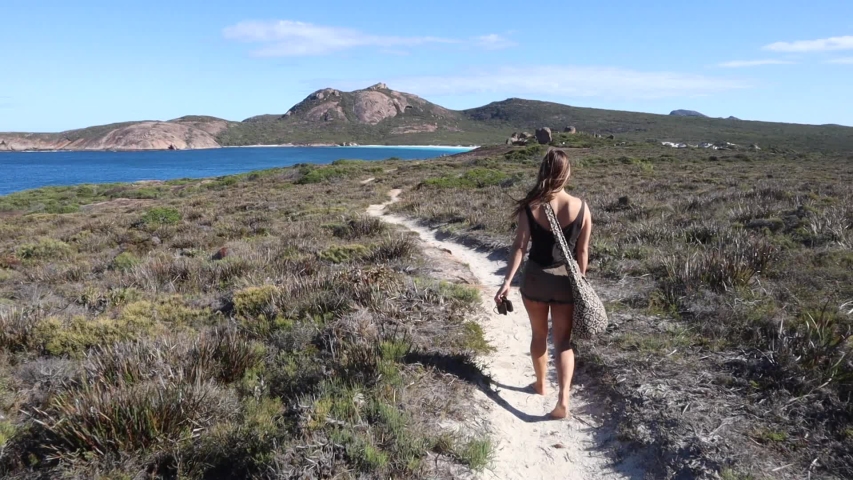 Young woman walking on national park trail with view of beautiful coastline