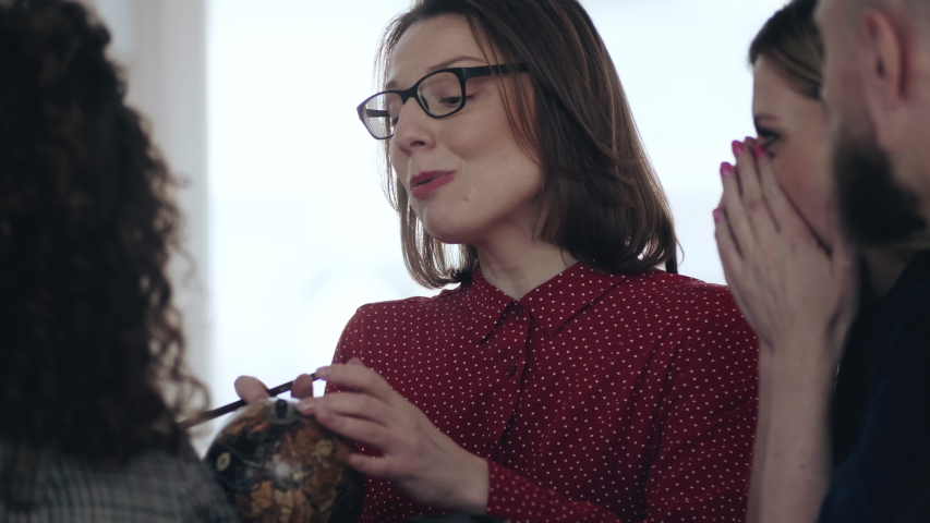 Beautiful middle aged Caucasian boss business woman talking to colleagues, pointing at little globe at loft office table