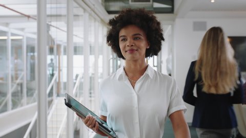 mixed race business woman smiling walking through office holding tablet computer enjoying successful career in corporate workplace 4k