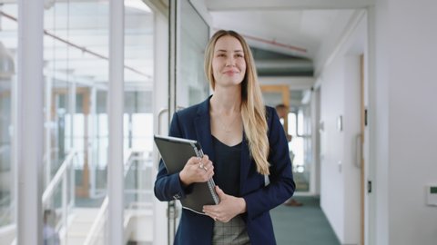 attractive blonde business woman smiling walking through office holding tablet computer enjoying successful leadership career in corporate workplace 4k