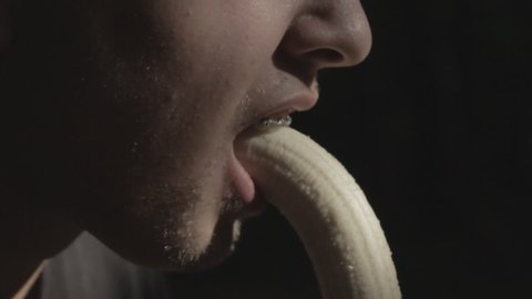 Person takes a bite off a banana in slow motion