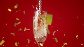 Digital composite of a glass of champagne with a pearl necklace against a red background while gold confetti fall in the screen - Powered by Shutterstock - Get 15% off with code: PIKWIZARD15