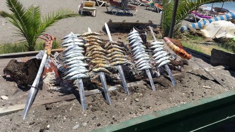 Sardine, octopus leg, squid on sticks on fire are fried in a boat. Typical "espetos" food of Spain, Costa del Sol, Malaga. Traditional food.