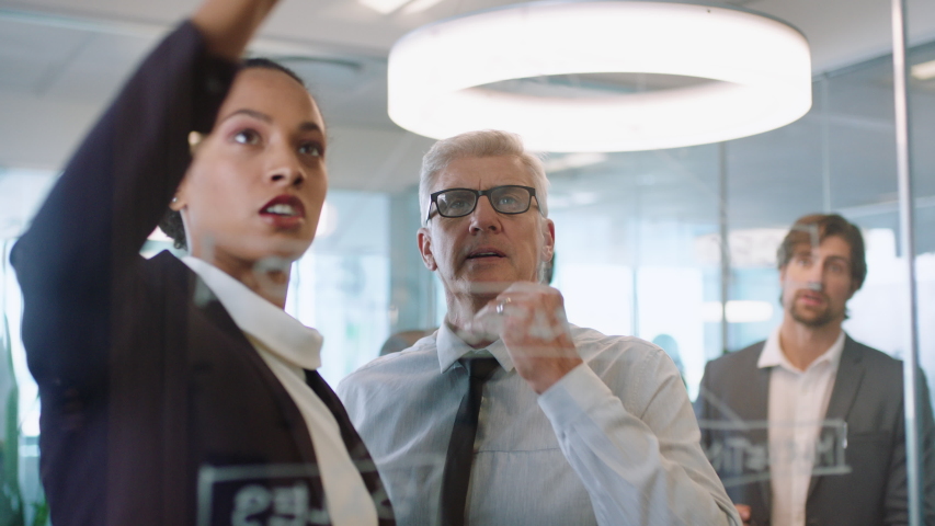 business people using sticky notes brainstorming team leader woman working with colleagues writing on glass whiteboard showing problem solving strategy in office meeting through glass