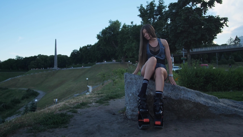 A beautiful girl dresses angoo jumps shoes. She is going to do sports in the park.