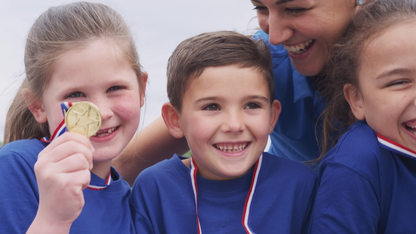 Children With Female Coach Showing Off Winners Medals On Sports Day