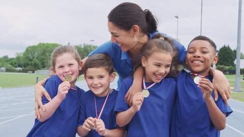 Children With Female Coach Showing Off Winners Medals On Sports Day