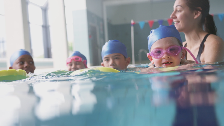 Female Coach In Water With Children Gives Swimming Lesson In Indoor Pool Royalty-Free Stock Footage #1033265216