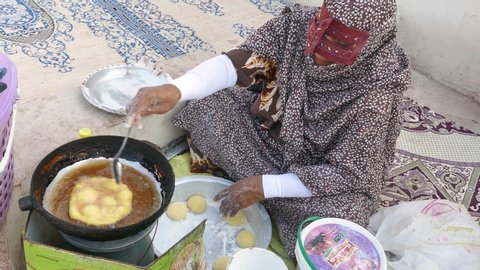Hormuz, Iran, July 2019: Muslim woman with islamic hijab burqa covering her face baking traditional bread in street