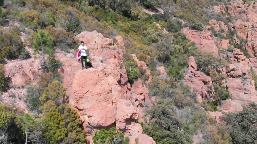 Orbit aerial view of a couple of tourists standing on top of mountain red rock.