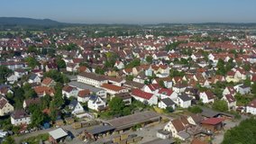 Aerial of the city Kirchheim unter Teck in Germany.  Camera zooms out, panorama of the city, with trees and green fields in the foreground.