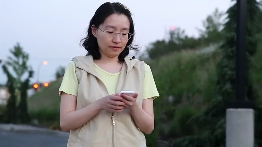 Port Coquitlam, BC, Canada - June 09, 2015 : Asian woman walking and reading information on cellphone | Shutterstock HD Video #10332896