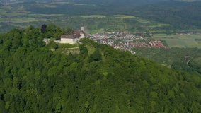 Aerial view of the castle burg Teck in Germany.  Camera pans right and rotates left, city in the background behind hilltop castle.
