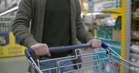 A man with a shopping cart goes to the supermarket in search of the right products.