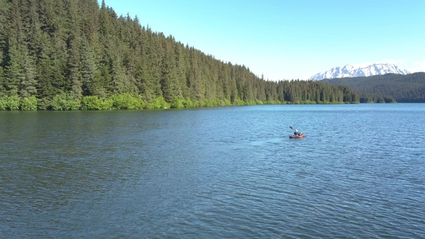 Aerial shot of a woman kayaking on beautiful mountain lake. Bear Lake, Seward, Alaska.